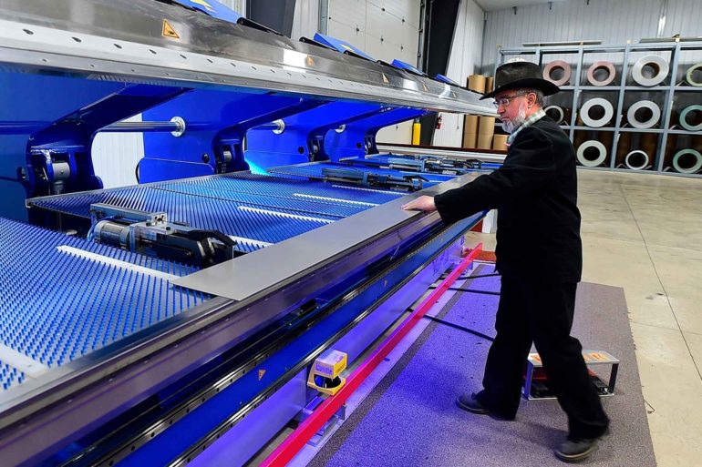 Dan Kleinsasser, of the Golden Valley Hutterite Colony near Ryegate, Mont. bends a steel roof at Valley Steel, LLC. (AP Photo, Larry Mayer)